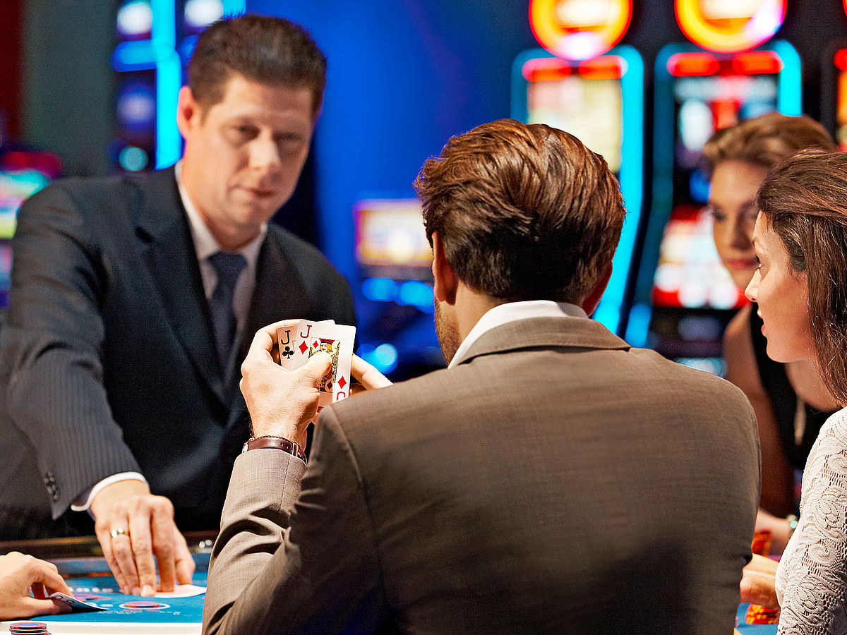 Mann am Pokertisch mit 2 Buben auf der Hand