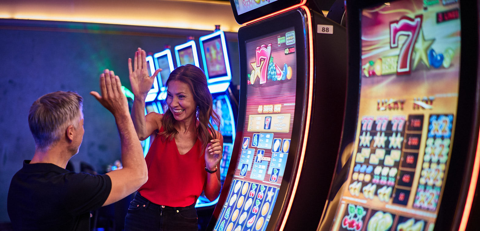 Mann und Frau feiern am Spielautomaten im Casino