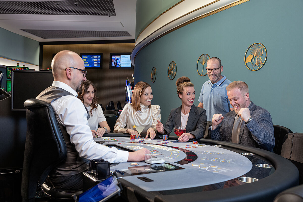 A group of people enjoying a lively poker game at a casino table. The dealer manages the game as players smile and engage, creating an upbeat atmosphere.
